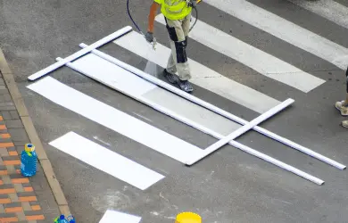 Worker painting car park line marking crosswalk