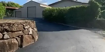 Asphalt driveway entrance with stone wall side