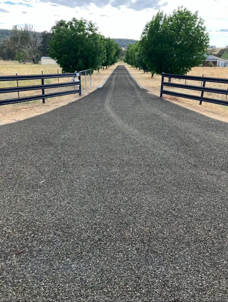 Long straight asphalt driveway with fences both sides