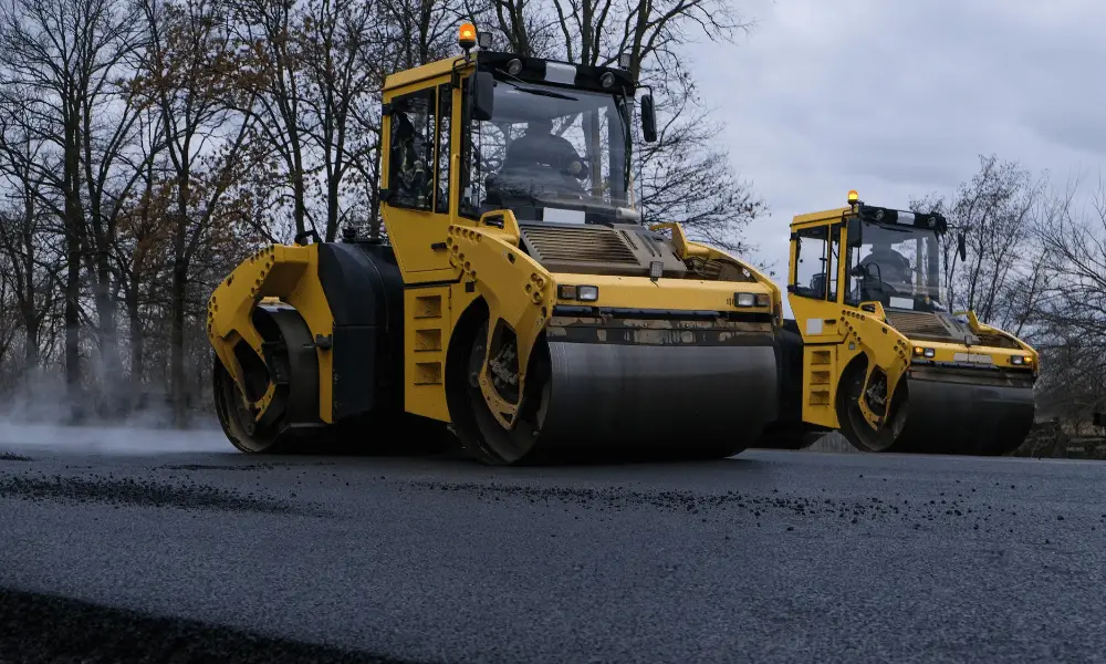 Two yellow construction machines on a road, highlighting construction activity