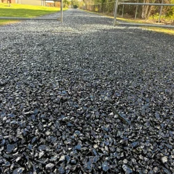 A close-up view of a gravel driveway composed of black gravel